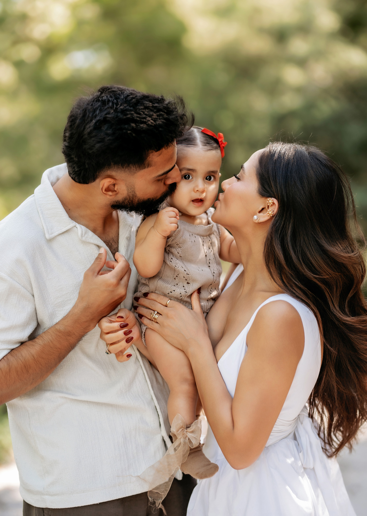 Parents kiss their daughter during sunset golden hour photoshoot in Central Florida